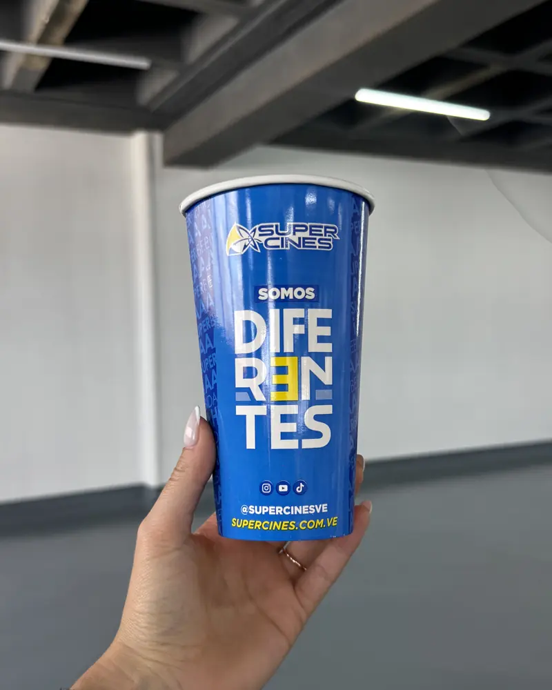 Vaso azul «Somos diferentes», sostenido frente a la maquinaria